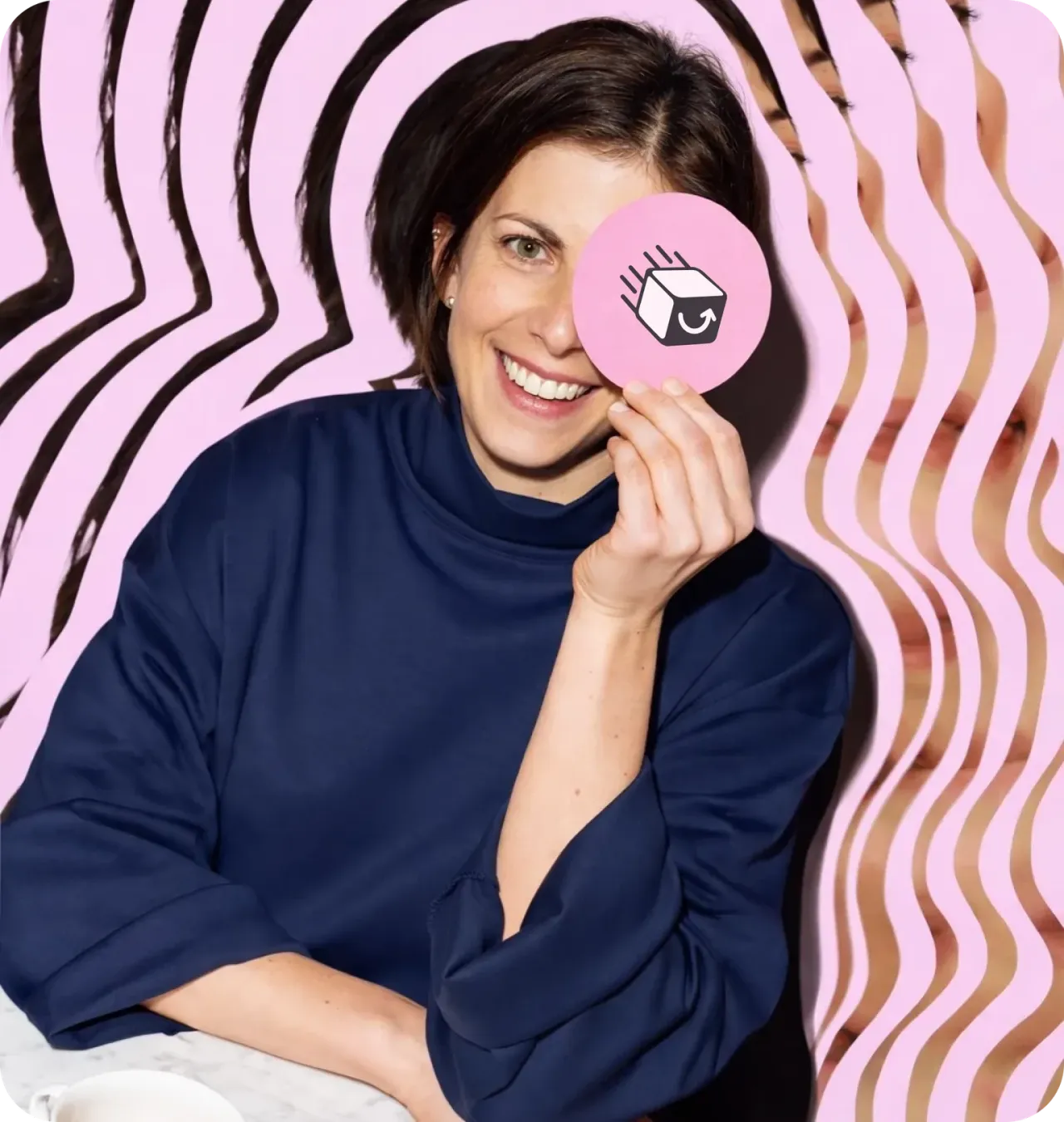 Retrato de uma colaboradora Bestmile sorrindo, segurando um adesivo circular rosa com o ícone da marca sobre o olho